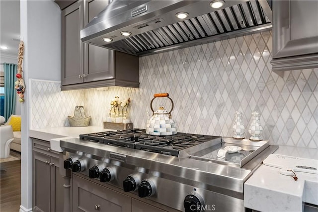 kitchen featuring backsplash, stainless steel gas stovetop, wall chimney exhaust hood, and gray cabinets