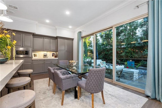 dining room with crown molding and light hardwood / wood-style flooring