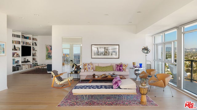 living room with hardwood / wood-style flooring, a wealth of natural light, and built in shelves