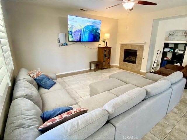 living room featuring a tile fireplace, ceiling fan, and light tile patterned flooring