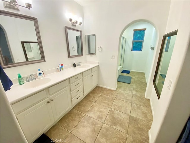 bathroom with a shower with door, vanity, and tile patterned floors