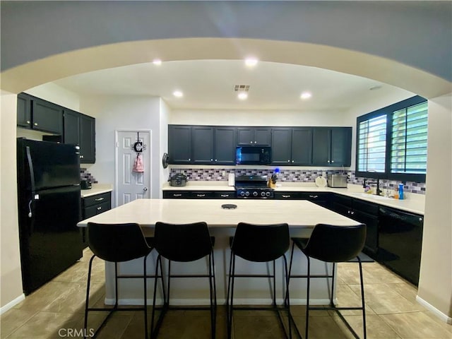 kitchen featuring light tile patterned flooring, black appliances, a kitchen breakfast bar, and a kitchen island