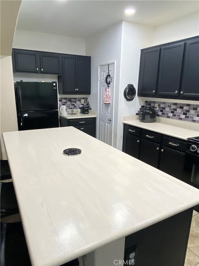 kitchen featuring tasteful backsplash, black fridge, and light tile patterned floors