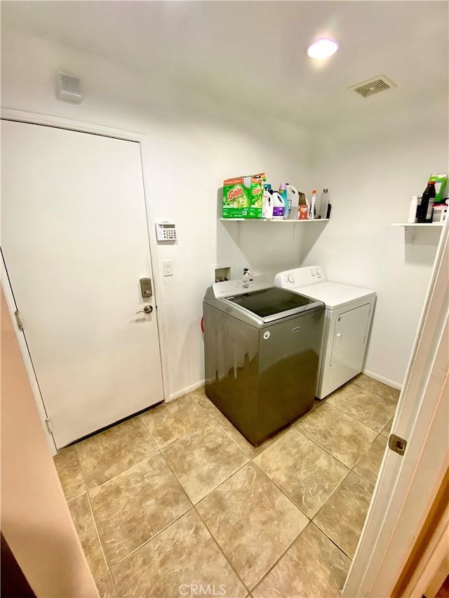 laundry area with washing machine and dryer and light tile patterned floors