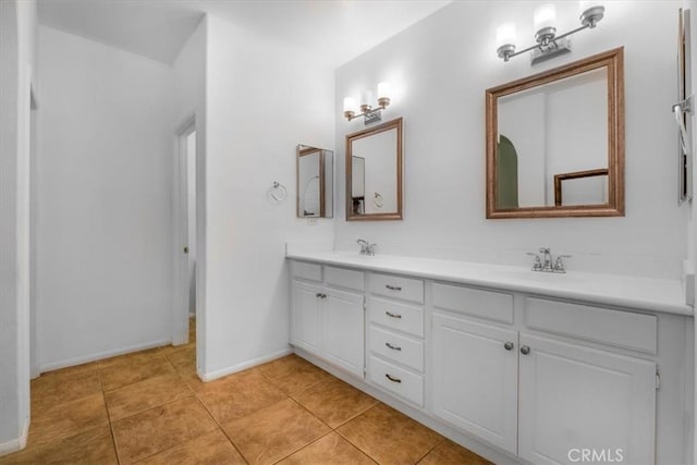 full bath with baseboards, tile patterned flooring, a sink, and double vanity