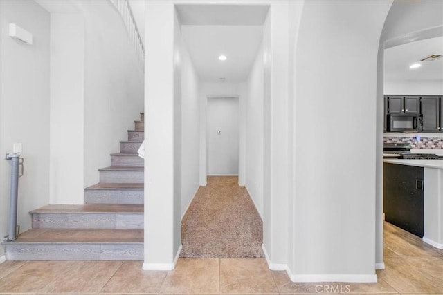 stairway with arched walkways, baseboards, tile patterned flooring, visible vents, and recessed lighting