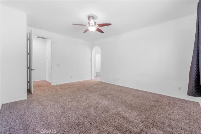 carpeted empty room with arched walkways, visible vents, and ceiling fan