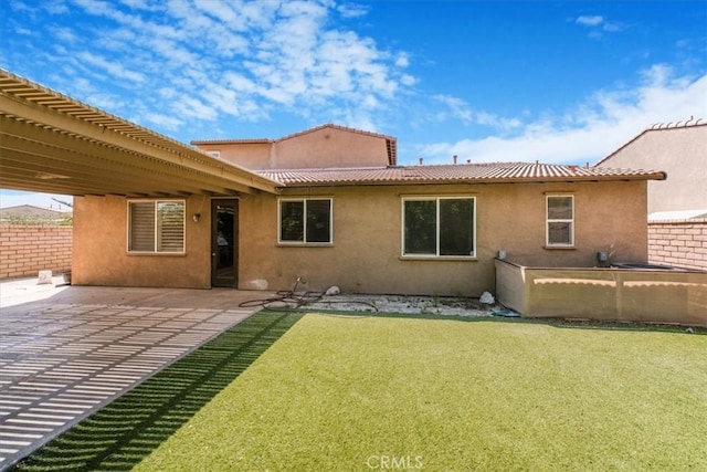 back of house with a lawn, a patio, stucco siding, and fence