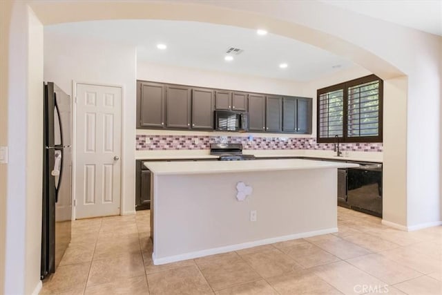 kitchen featuring arched walkways, visible vents, decorative backsplash, light countertops, and black appliances