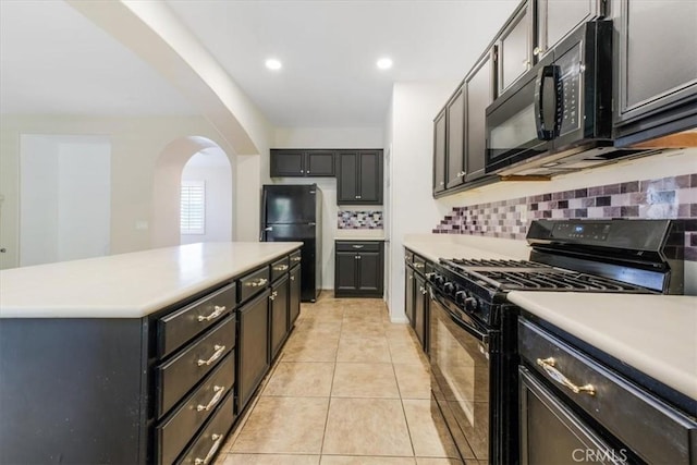 kitchen featuring decorative backsplash, light countertops, arched walkways, and black appliances
