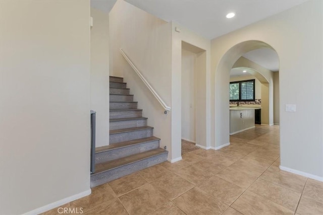 stairs featuring tile patterned flooring, baseboards, arched walkways, and recessed lighting