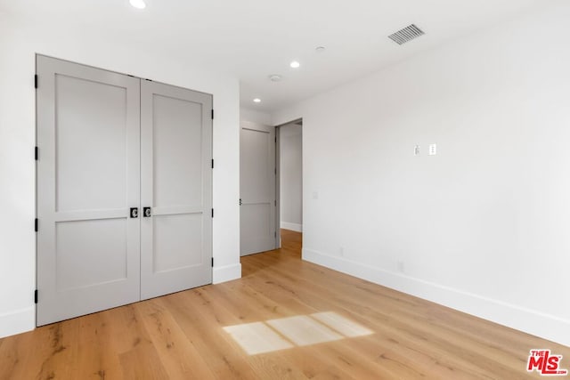 unfurnished bedroom with a closet and light hardwood / wood-style flooring