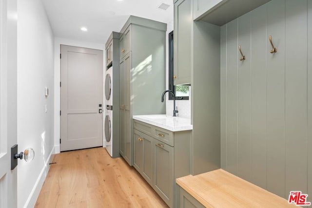 interior space featuring stacked washer and clothes dryer, sink, and light hardwood / wood-style flooring