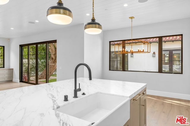 kitchen featuring light stone counters, wood ceiling, decorative light fixtures, and sink