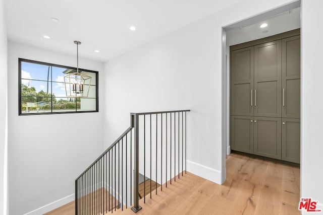 corridor featuring a notable chandelier and light wood-type flooring