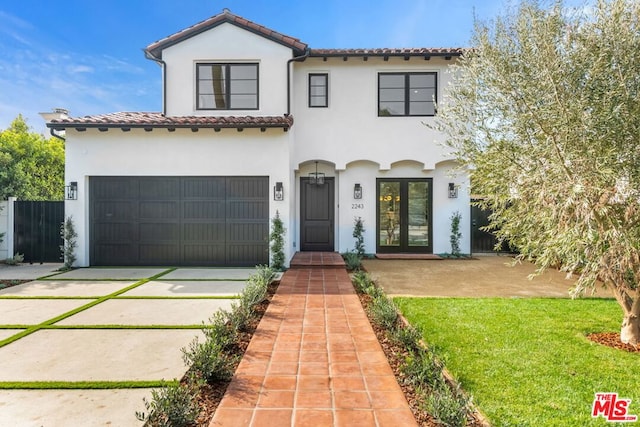 mediterranean / spanish house featuring a garage and a front lawn