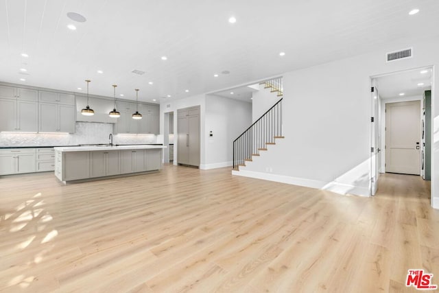 unfurnished living room with sink and light hardwood / wood-style flooring