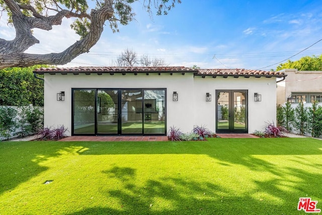 back of house featuring french doors and a lawn