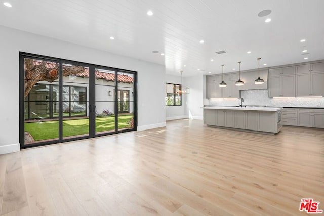 unfurnished living room featuring sink, light hardwood / wood-style floors, and wooden ceiling