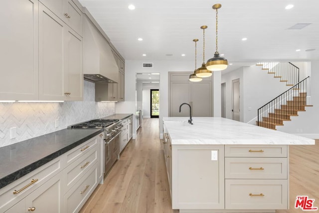 kitchen with a spacious island, stainless steel range, custom exhaust hood, and pendant lighting