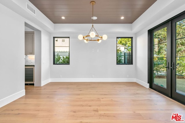 spare room featuring an inviting chandelier, wooden ceiling, french doors, and light wood-type flooring