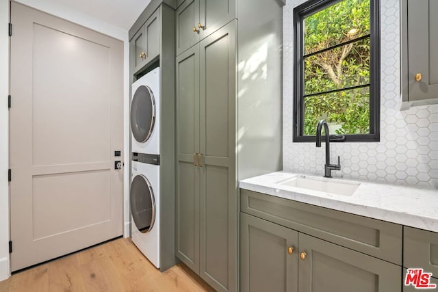 washroom featuring light wood-type flooring, cabinets, sink, and stacked washer and dryer