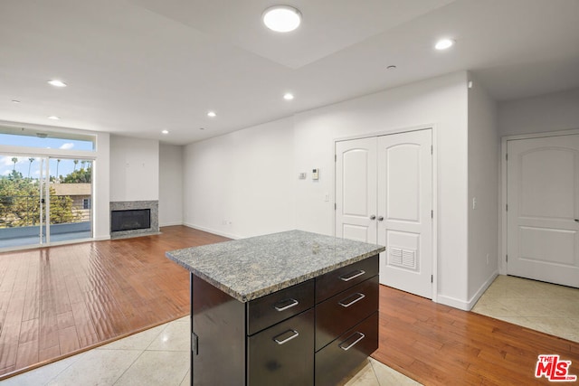 kitchen featuring light stone countertops, a center island, light tile patterned floors, and dark brown cabinetry