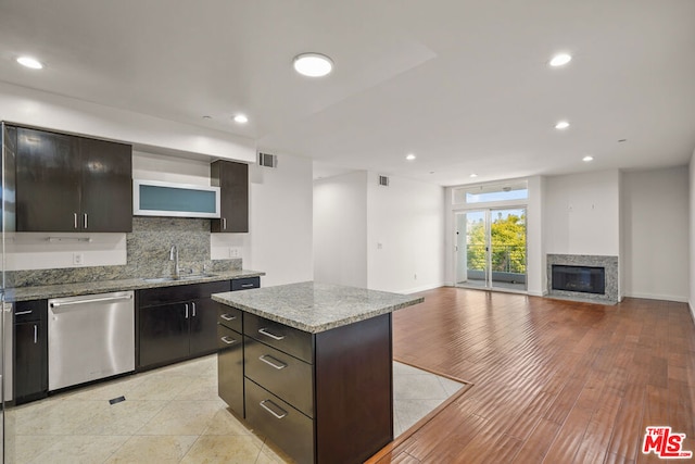 kitchen with sink, dark brown cabinets, tasteful backsplash, a kitchen island, and stainless steel dishwasher