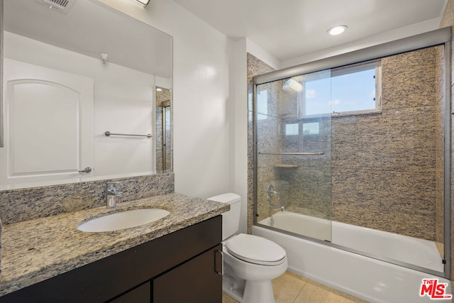 full bathroom featuring toilet, tile patterned floors, vanity, and bath / shower combo with glass door