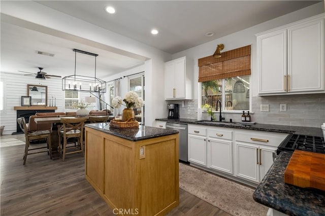 kitchen featuring sink, decorative light fixtures, a center island, stainless steel dishwasher, and white cabinets