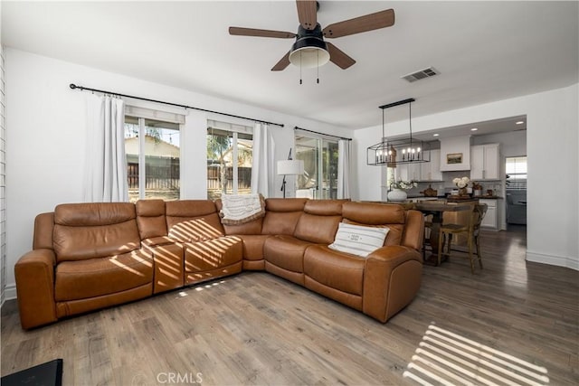 living room featuring hardwood / wood-style flooring, a wealth of natural light, and ceiling fan with notable chandelier