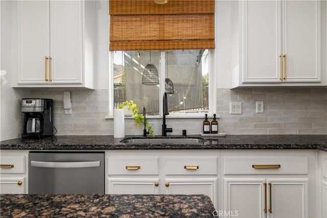 kitchen featuring dishwasher, sink, white cabinets, backsplash, and dark stone counters