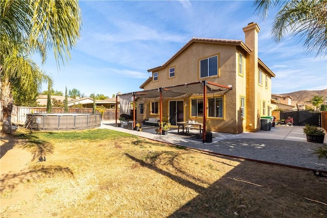 back of property with a fenced in pool, a patio, central AC, and a pergola