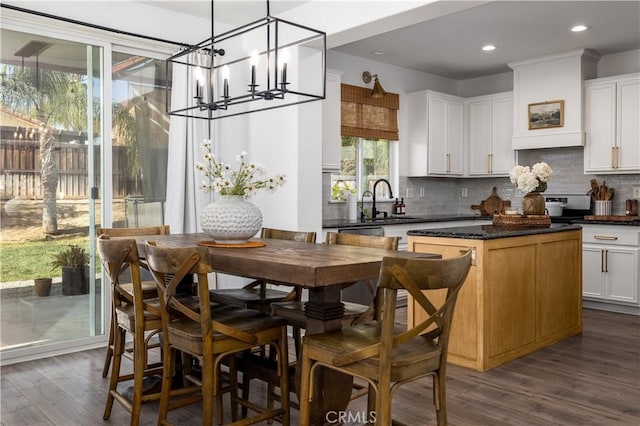 kitchen with dark hardwood / wood-style floors, white cabinetry, sink, hanging light fixtures, and a center island