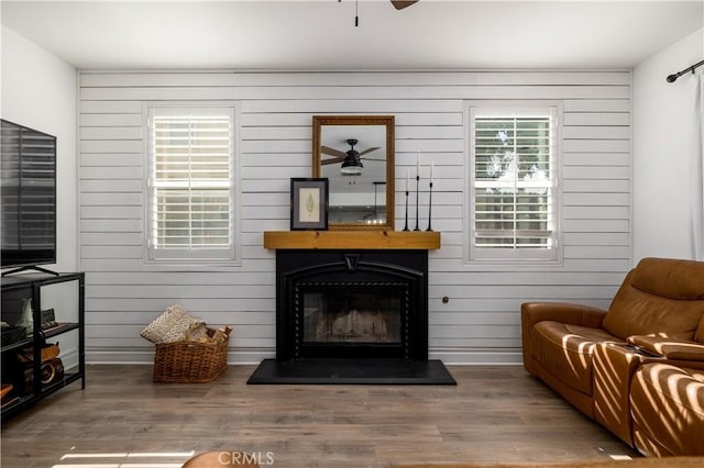 living room with ceiling fan, hardwood / wood-style floors, and wood walls