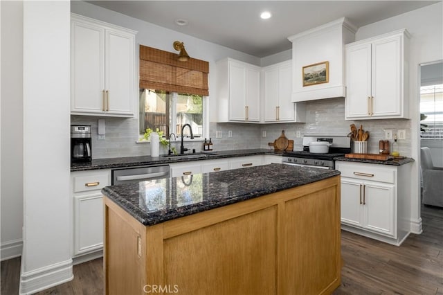 kitchen with sink, appliances with stainless steel finishes, dark hardwood / wood-style floors, a kitchen island, and white cabinets