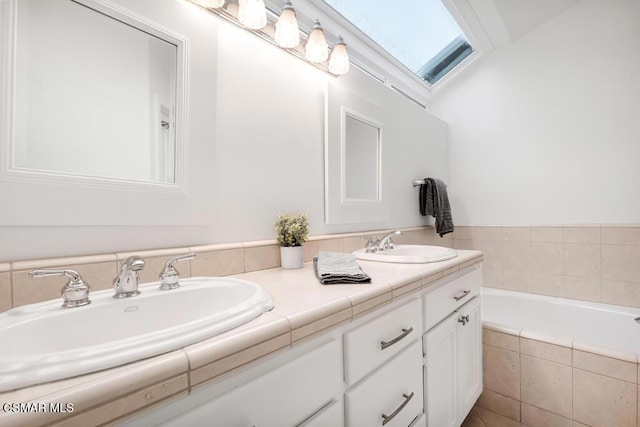 bathroom featuring tiled tub and vanity