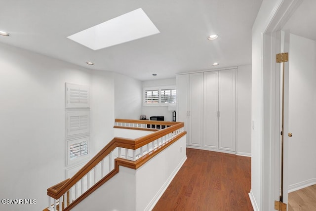 hallway with light hardwood / wood-style flooring and a skylight