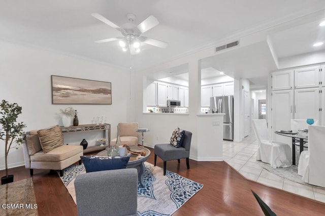 living room with ceiling fan, ornamental molding, and light hardwood / wood-style flooring