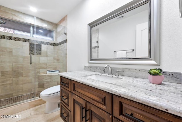 bathroom featuring vanity, tile patterned flooring, toilet, and walk in shower