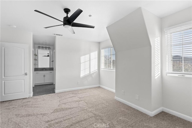 interior space featuring carpet, connected bathroom, and ceiling fan