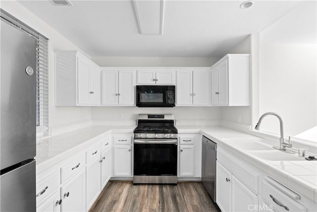 kitchen with dark wood-type flooring, sink, white cabinetry, appliances with stainless steel finishes, and tile counters