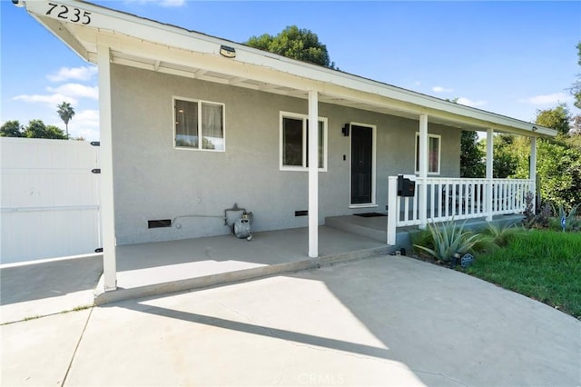 ranch-style home with stucco siding, covered porch, and crawl space