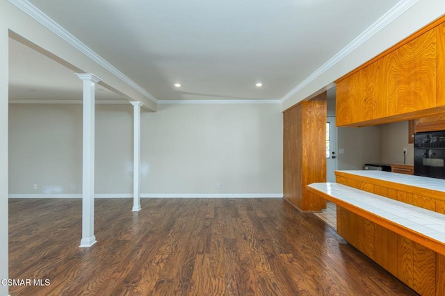 kitchen with black oven, dark hardwood / wood-style floors, ornamental molding, tile countertops, and ornate columns