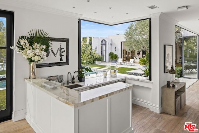 interior space featuring expansive windows, sink, and light wood-type flooring