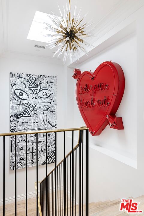 stairs with an inviting chandelier, ornamental molding, and hardwood / wood-style flooring