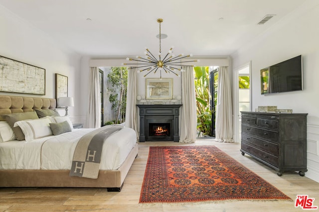 bedroom featuring access to exterior, a notable chandelier, and light hardwood / wood-style flooring