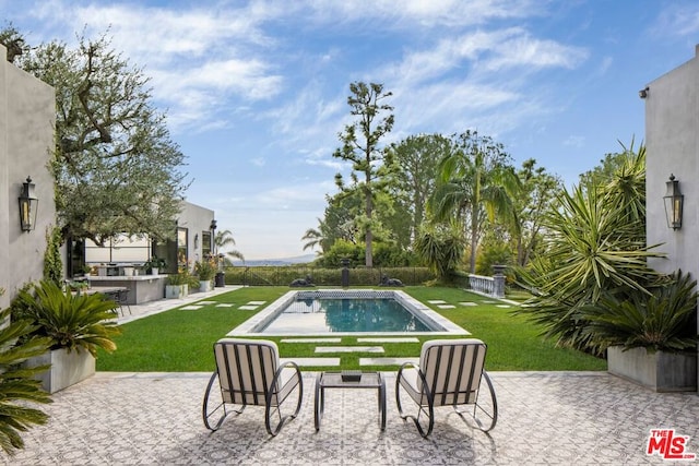 view of swimming pool featuring a lawn, a patio, and exterior kitchen