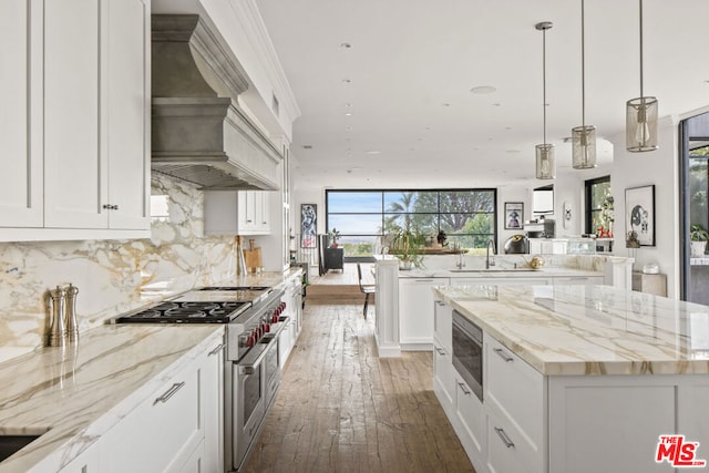 kitchen featuring white cabinets, decorative backsplash, double oven range, a center island, and custom range hood