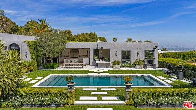 back of property featuring a patio area, a lawn, and an outdoor kitchen